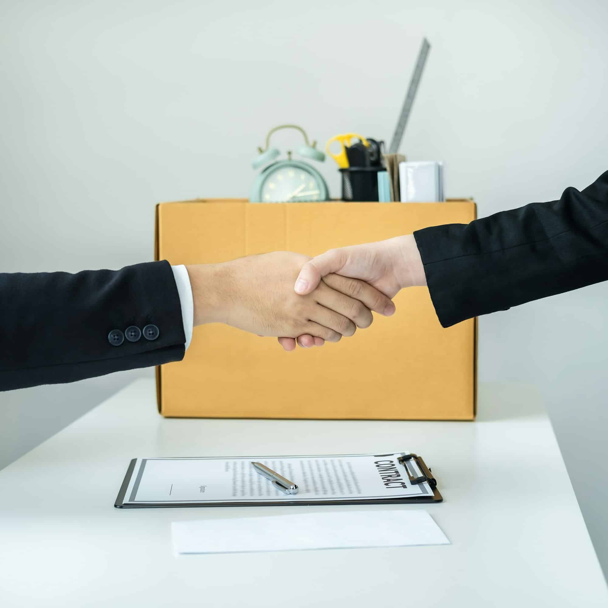 business woman employee in suit shaking hands with boss after signing on resignation letter